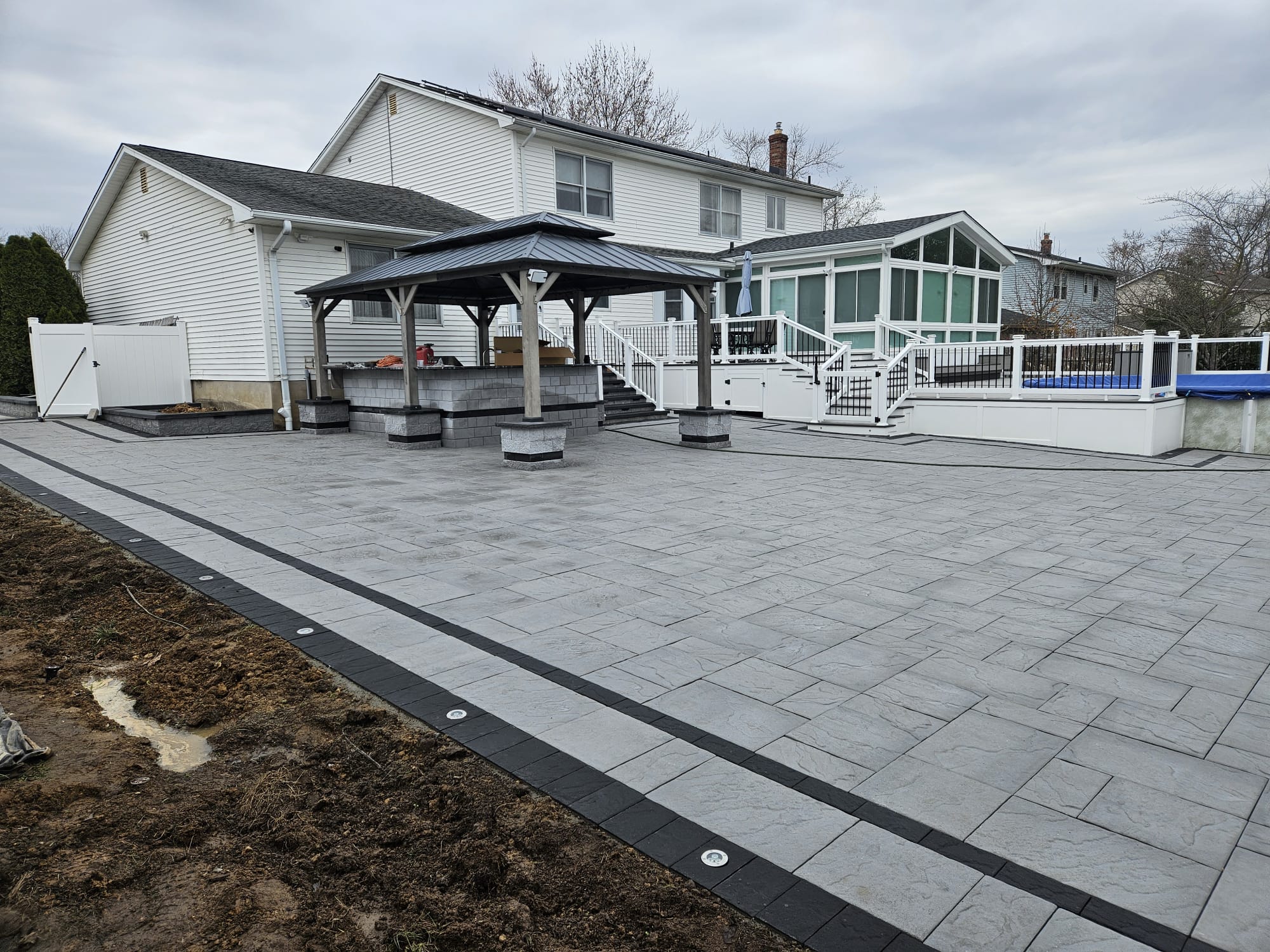 Paver patio and pergola beside a residential home